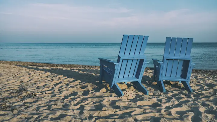 two wooden deck chairs on a beach