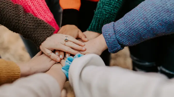 people putting their hands together in a group huddle
